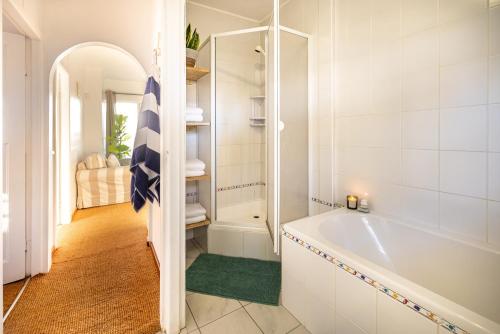 uma casa de banho branca com uma banheira e um chuveiro em Swakopmund Seafront Cottage em Swakopmund