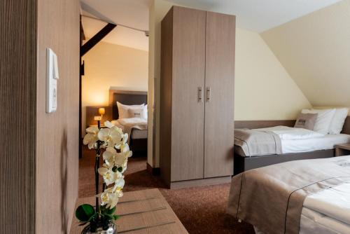 a hotel room with two beds and a vase with flowers at Novum Hotel Alster Hamburg St. Georg in Hamburg