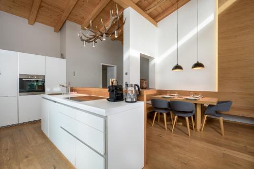 a kitchen with white cabinets and a table and chairs at Ski & Golf Auszeit Apartment by Alpine Host Helpers in Kitzbühel