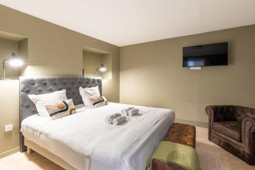 une chambre avec un grand lit blanc et une chaise dans l'établissement NEW - Appartement Luxeux avec Cinema et Sauna, à Paris