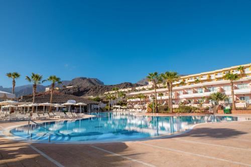 a large swimming pool with palm trees and a hotel at Landmar Costa los Gigantes in Puerto de Santiago