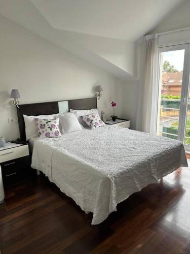 a white bedroom with a bed and a window at Excepcional chalet en Perbes. in Miño