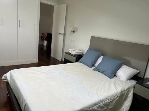 a bedroom with a large bed with two blue pillows at Excepcional chalet en Perbes in Miño