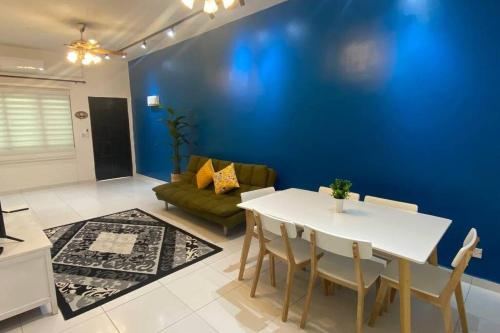 een woonkamer met een witte tafel en een blauwe muur bij R&R Manjung Guest House at Pangsapuri Samudera in Seri Manjung