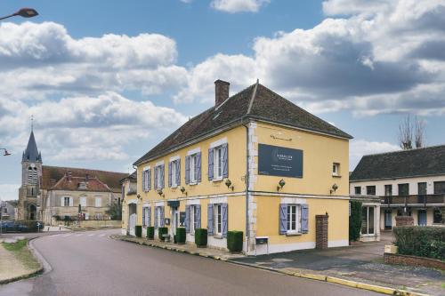 un bâtiment jaune sur le côté d'une rue dans l'établissement LOGIS Hôtel & Restaurant Le Soleil D'or, à Montigny-la-Resle