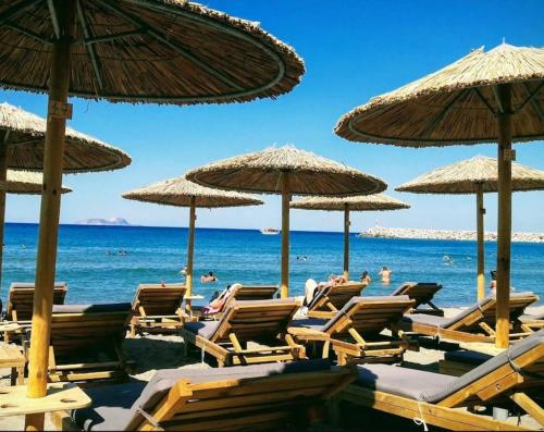 a bunch of chairs and umbrellas on a beach at Creta Irini's Rooms Παραδοσιακά for you in Tympáki