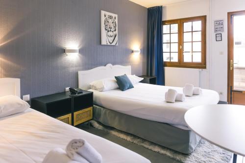 Habitación de hotel con 2 camas y mesa en LOGIS Hôtel & Restaurant Le Soleil D'or en Montigny-la-Resle