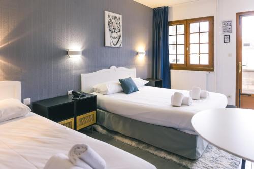 Montigny-la-ResleにあるLOGIS Hôtel & Restaurant Le Soleil D'orのベッド2台とテーブルが備わるホテルルームです。