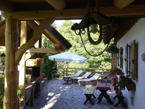 an outdoor patio with chairs and an umbrella and benches at Holiday House Sobol in Kuželj