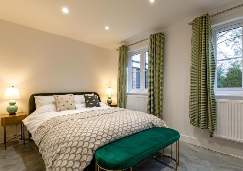 a bedroom with a bed and two windows with green curtains at Haons in Biddenden
