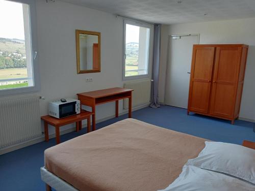 a bedroom with a bed and a desk and window at L'Atelier Obelix familiale de 1 à 4 personnes in Saint-Symphorien-de-Marmagne