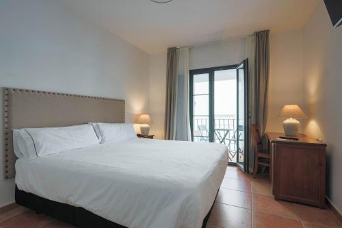1 dormitorio con 1 cama blanca grande y balcón en Hotel Tugasa Sierra y Cal, en Olvera