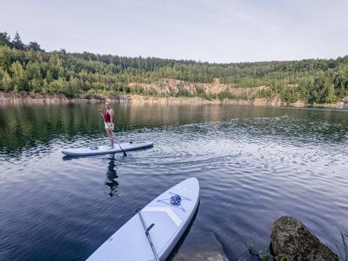 a person standing on a paddle board on a lake at HW4B - Urlaubsmagie - Zentral mit Gemeinschaftsgarten, -Pool, -Sauna & Whirlpool in Sebnitz
