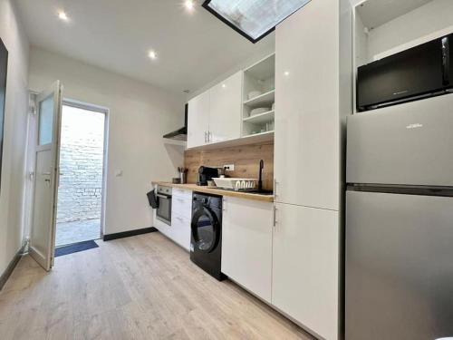  La cuisine est équipée de placards blancs et d'un réfrigérateur. dans l'établissement Maison Lilloise 6 personnes cœur de Roubaix, à Roubaix