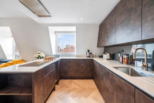 a kitchen with wooden cabinets and a large window at Marble Arch Penthouse 2 Bed in London