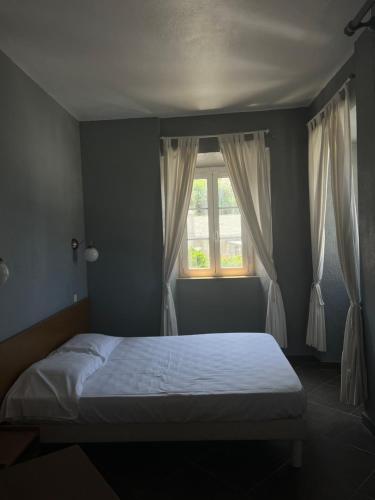 een slaapkamer met een bed en een raam met gordijnen bij L’Auberge du pêcheur in Centuri