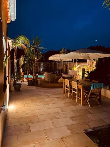 un patio avec tables, chaises et un parasol dans l'établissement Valbonne, villa avec piscine, à Valbonne