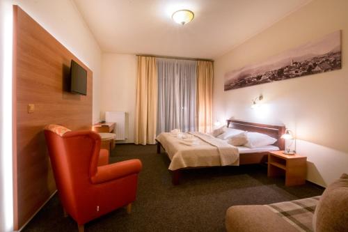 een hotelkamer met een bed en een stoel bij Penzión Ľadoveň SKVELÁ KUCHYŇA A RODINNÁ ATMOSFÉRA in Martin