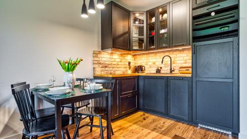 a kitchen with black cabinets and a table with chairs at Apartamenty z basenem i saunami STONE HILL RESORT II VIP Centrum by Royal Aparts in Szklarska Poręba