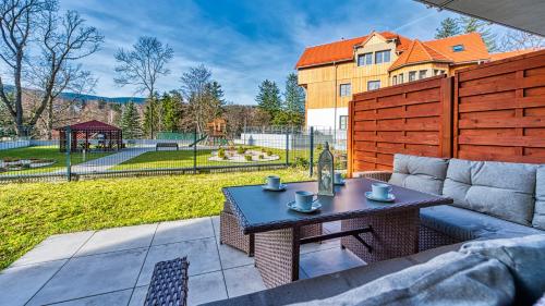 a patio with a couch and a table and a playground at Apartamenty z basenem i saunami STONE HILL RESORT II VIP Centrum by Royal Aparts in Szklarska Poręba