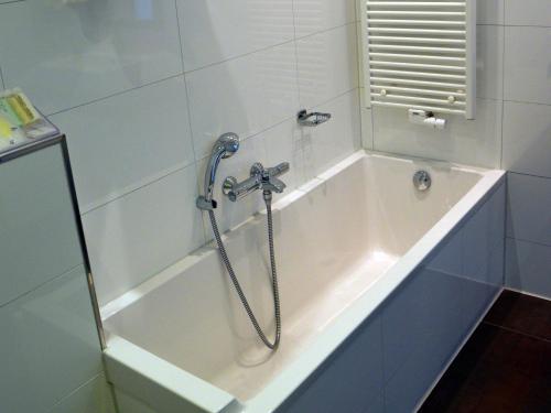 a bath tub with a shower in a bathroom at Golden Tulip West Ende in Helmond