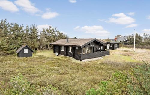 a black house in a field with trees at 3 Bedroom Amazing Home In Ringkøbing in Ringkøbing