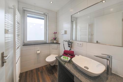 a white bathroom with a sink and a toilet at Hotel Gästehaus Stock Zimmer Trüffeleckle in Friedrichshafen