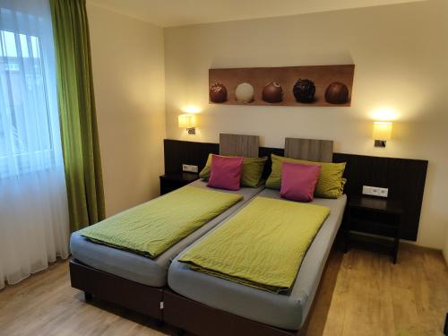 a bedroom with a bed with pink and green pillows at Hotel Stock Trüffeleckle in Friedrichshafen