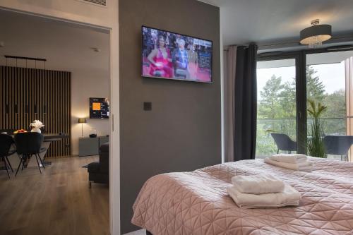 a bedroom with a bed with a tv on the wall at Apartament Premium PINEA 313 in Pobierowo