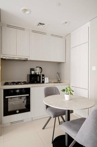 a kitchen with white cabinets and a table with chairs at Pool View One Bed Room Business Bay in Dubai