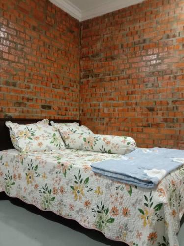 a bed in a room with a brick wall at D GARDEN HOME STAY in Tanah Merah