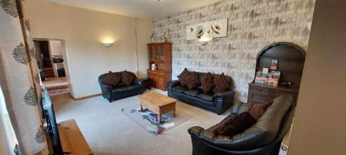 a living room with two couches and a table at Cae Berllan Cottages in Groeslon