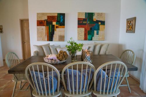 a dining room table with four chairs and a table with a bowl at Villa Blue Hole in Mangrove Cay