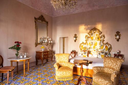 a bedroom with a large bed and chairs and a mirror at Villa De Cillis Carafa in Torre del Greco