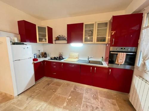 une cuisine avec des armoires rouges et un réfrigérateur blanc dans l'établissement Maison Cosy Intra-muros, clim, parking, extérieur, à Aigues-Mortes