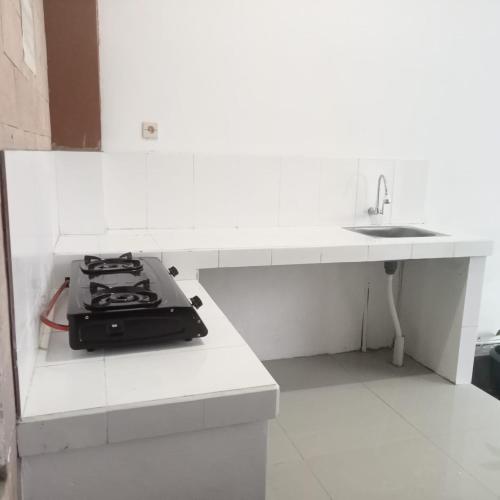 a white kitchen with a stove and a sink at Bima guest house in Ngadipuro