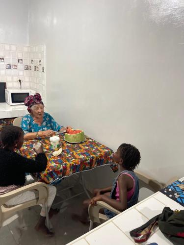 a woman and two children sitting at a table at Auberge Andel Diabou SARR in Palmarin