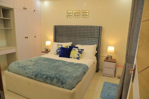 een slaapkamer met een groot bed met blauwe kussens bij Gail Homes Naalya - One bedroom luxury apartment in Kampala