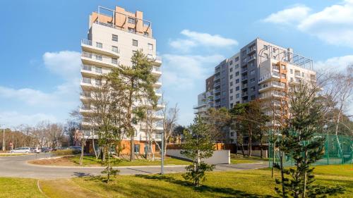 two tall buildings in a park next to a street at Comfy Apartments - Morska Bryza in Gdańsk
