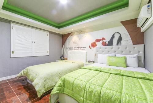a bedroom with two beds with green sheets and a poster at Jara Changwon in Changwon