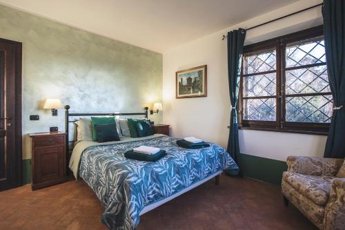a bedroom with a bed and a chair and a window at CASALE LE CIVETTE in Montepulciano