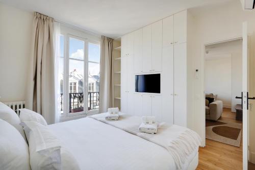 - une chambre blanche avec un grand lit et une télévision dans l'établissement Pick A Flat's Apartment in Saint Michel - Rue Du Sommerard, à Paris