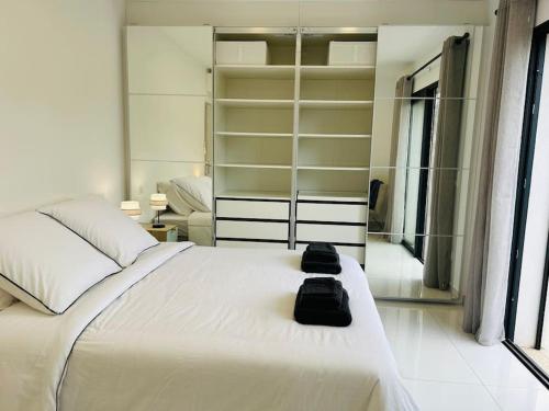 - une chambre dotée d'un lit blanc avec deux sacs dans l'établissement Villa Climatisée avec Piscine partagée , Terrasse et Parking, à Prunelli-di-Fiumorbo