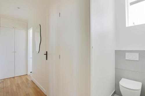 La salle de bains blanche est pourvue de toilettes et d'une porte. dans l'établissement Pick A Flat's Apartment in Saint Michel - Rue Du Sommerard, à Paris