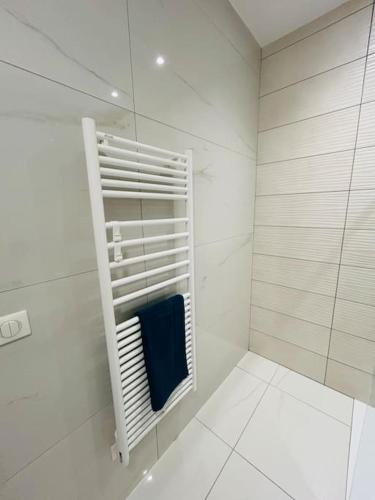 La salle de bains blanche est pourvue d'une douche et d'une serviette bleue. dans l'établissement Villa Climatisée avec Piscine partagée , Terrasse et Parking, à Prunelli-di-Fiumorbo