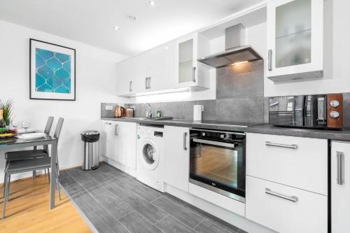 a kitchen with white cabinets and a table and a stove at City Centre Penthouse - Large Balcony - 2 Bedroom - Secure Parking 1001M in Birmingham