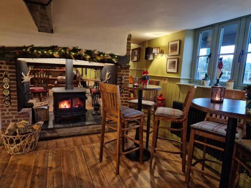 a living room with a fireplace and tables and chairs at The Duke on The Test in Romsey