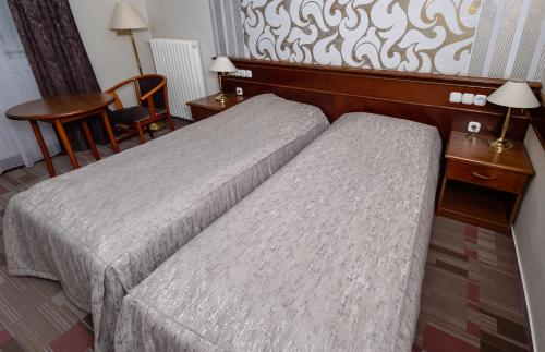 a hotel room with two beds and a chair at Arany Bárány Hotel in Zalaegerszeg