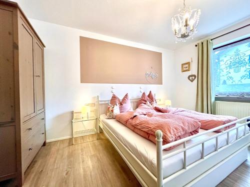 um quarto com uma cama com lençóis cor-de-rosa e um lustre em Goldener Hahn Baiersbronn - Ferienwohnungen mit Hotel Service em Baiersbronn