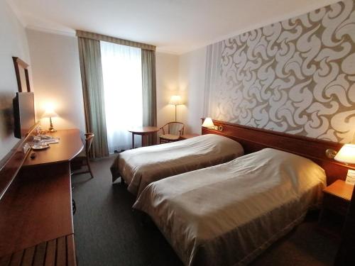 a hotel room with two beds and a desk at Arany Bárány Hotel in Zalaegerszeg